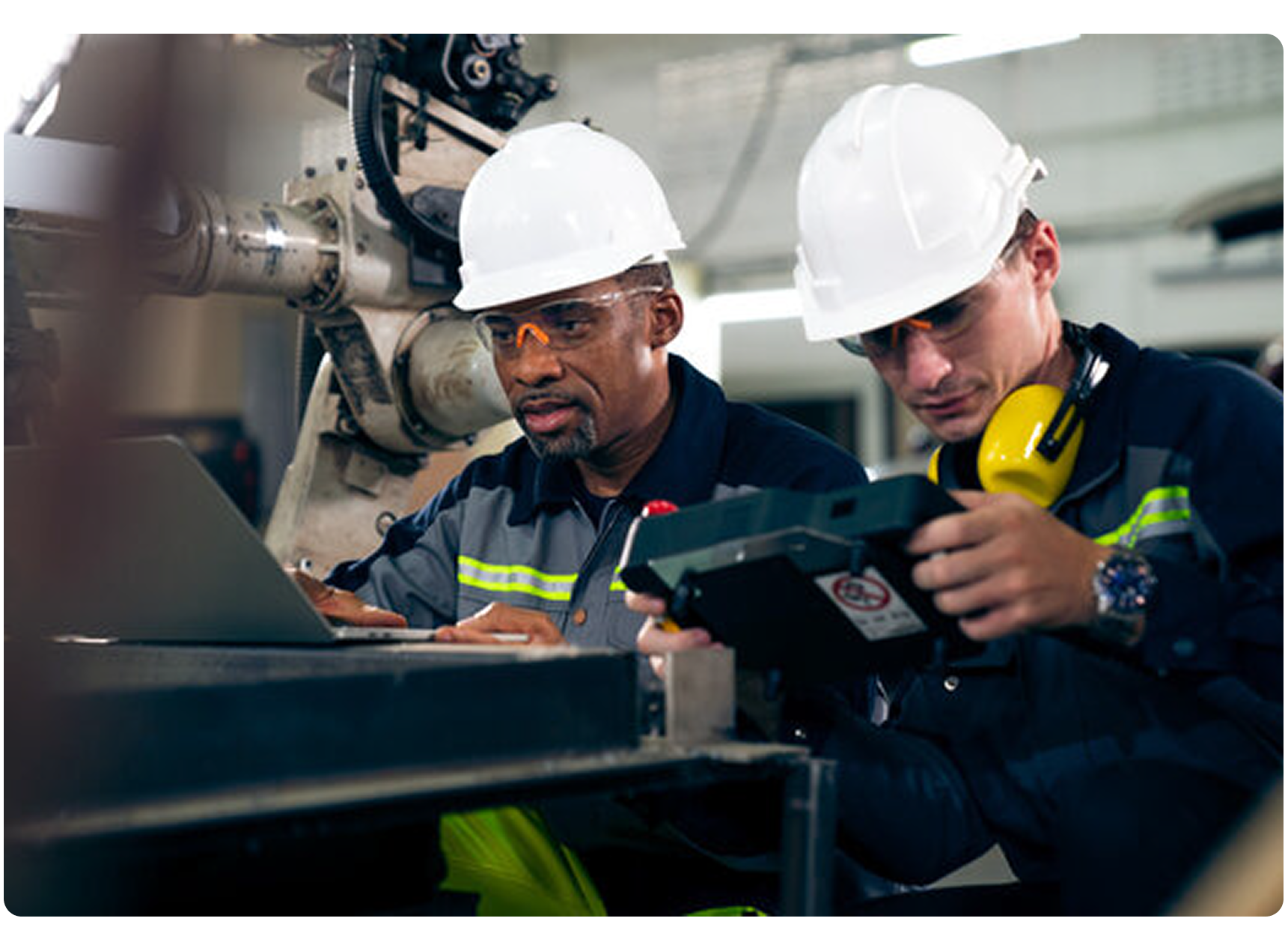 Two shop floor workers looking at a laptop and plant