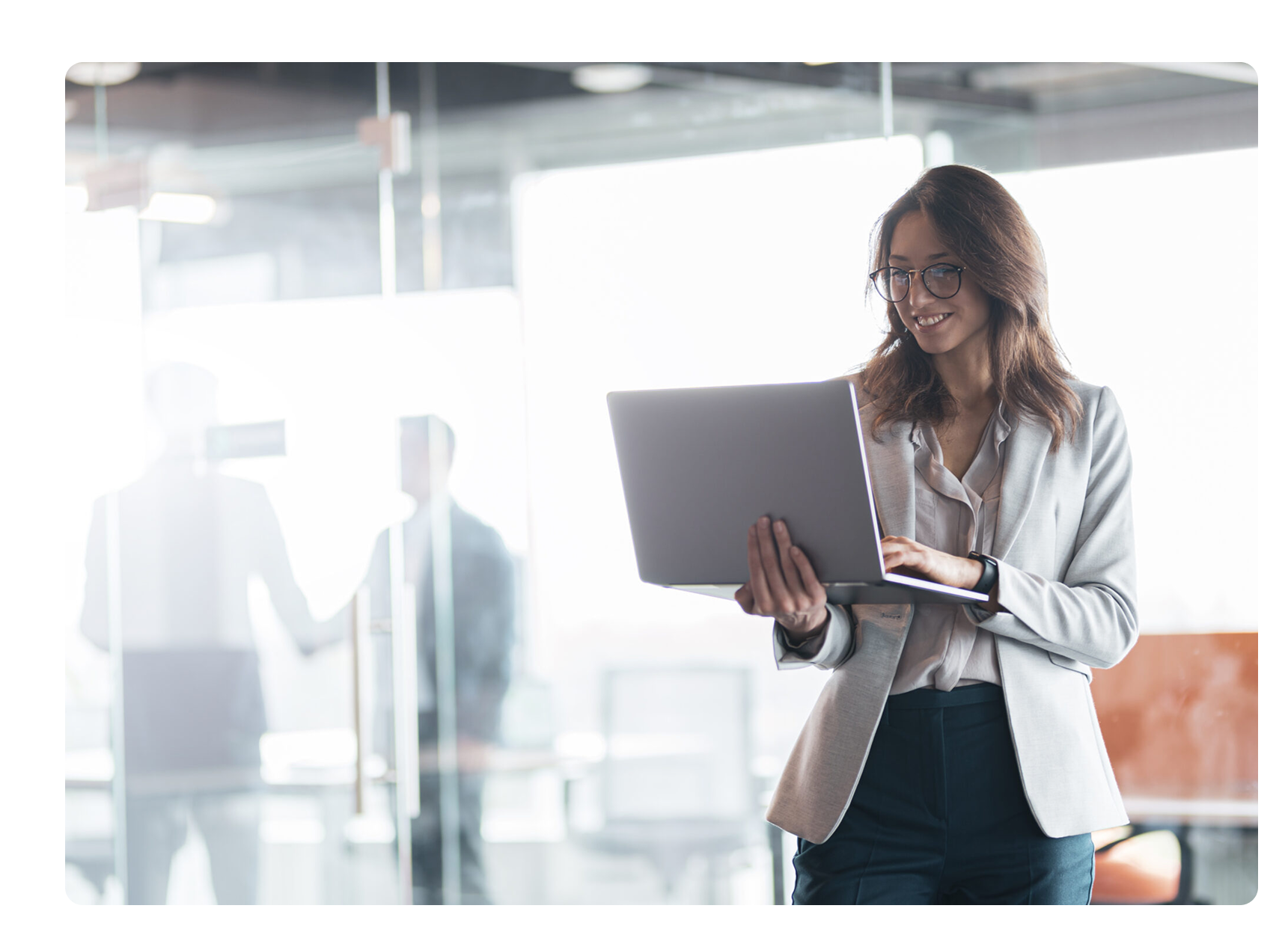 woman walking and looking at her laptop smiling